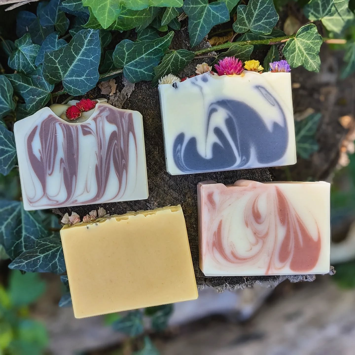 Four swirled soap bars on a natural background with green leaves