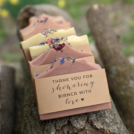 Handmade soap bars with floral decorations on top, wrapped in brown kraft paper with text 'THANK YOU FOR SHOWERING BIANCA WITH love'.