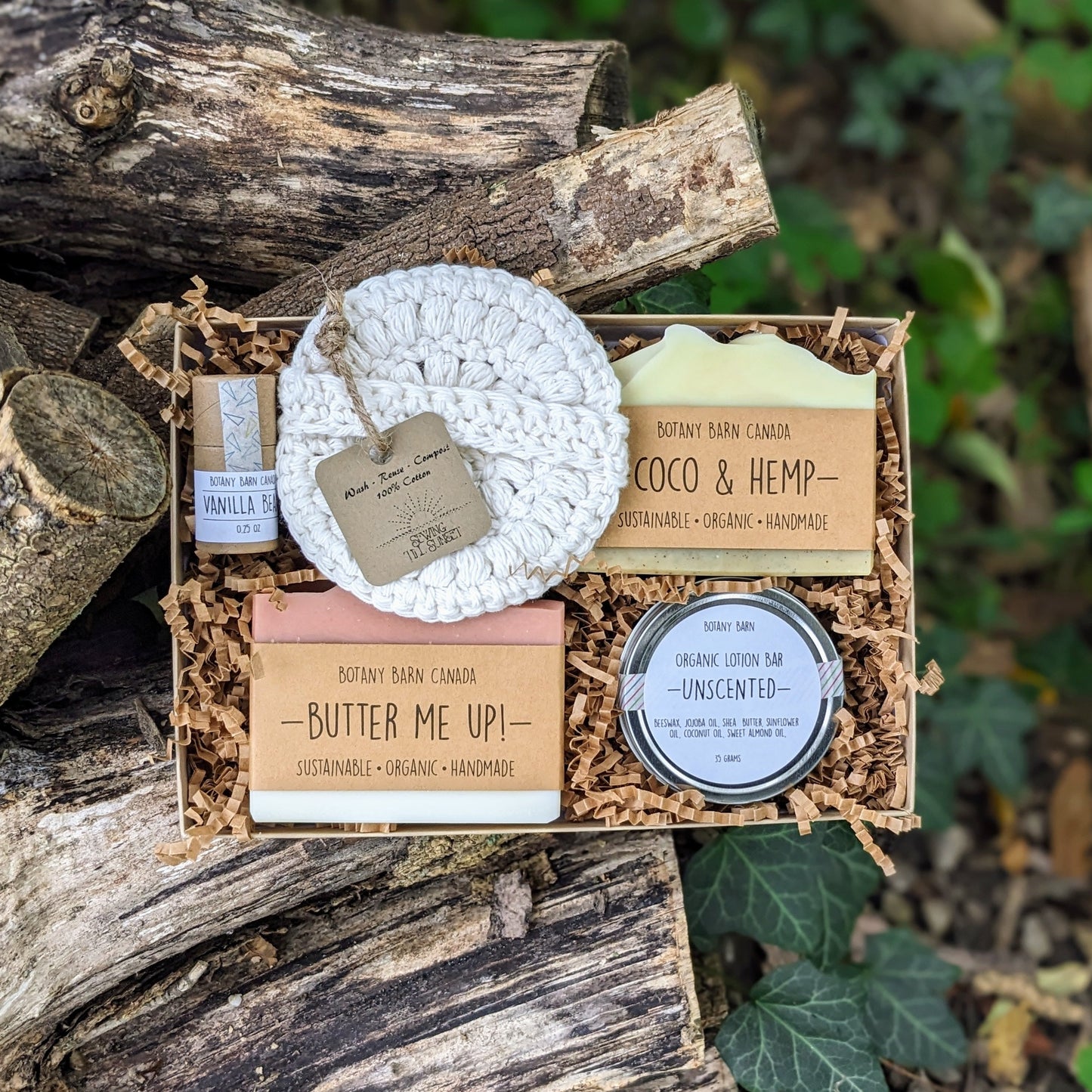 A gift box containing soap bars, lotion bar in a metal tin, lip balm, and crocheted facial round, with Botany Barn branding.