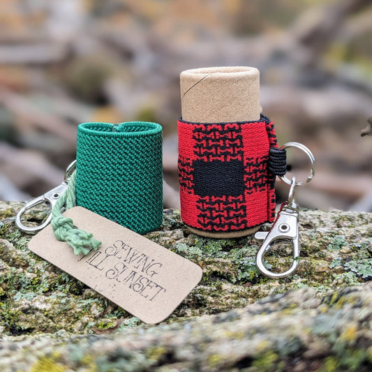 Two lip balm holders attached to keychains, one green and one red, displayed on a wooden surface.