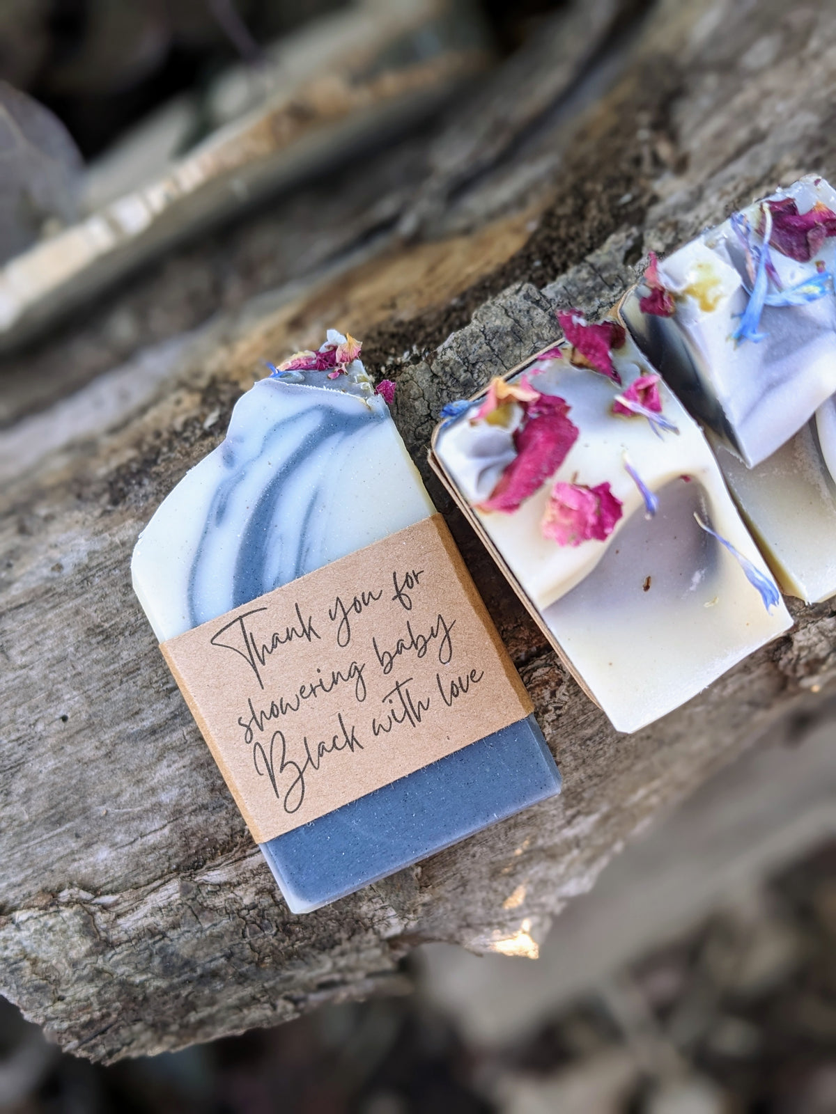 Handmade soap bars with floral petals on a rustic wooden surface