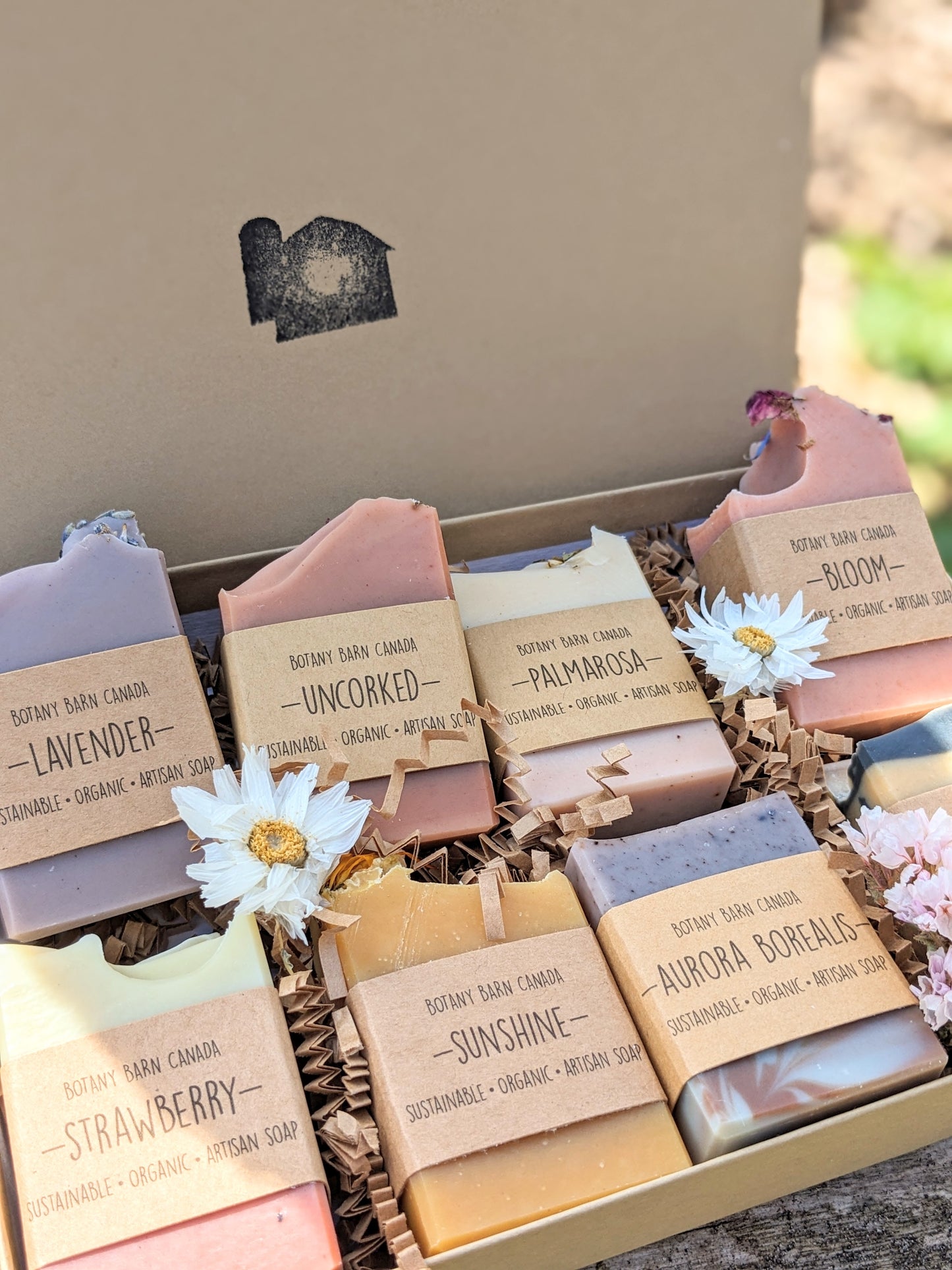 A gift box containing eight different handmade soaps, each with their own label and color, arranged in two rows.