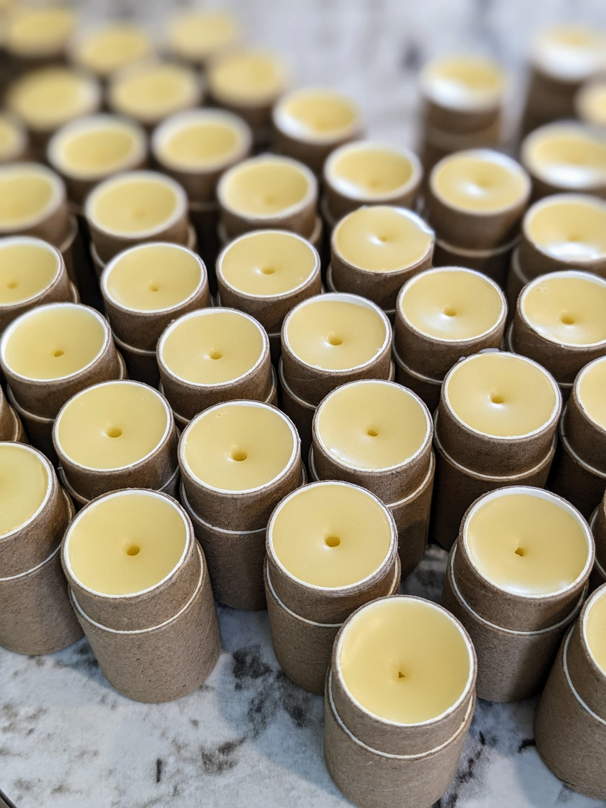 Lip balms are displayed without the caps, pale yellow balm is visible inside each tube.