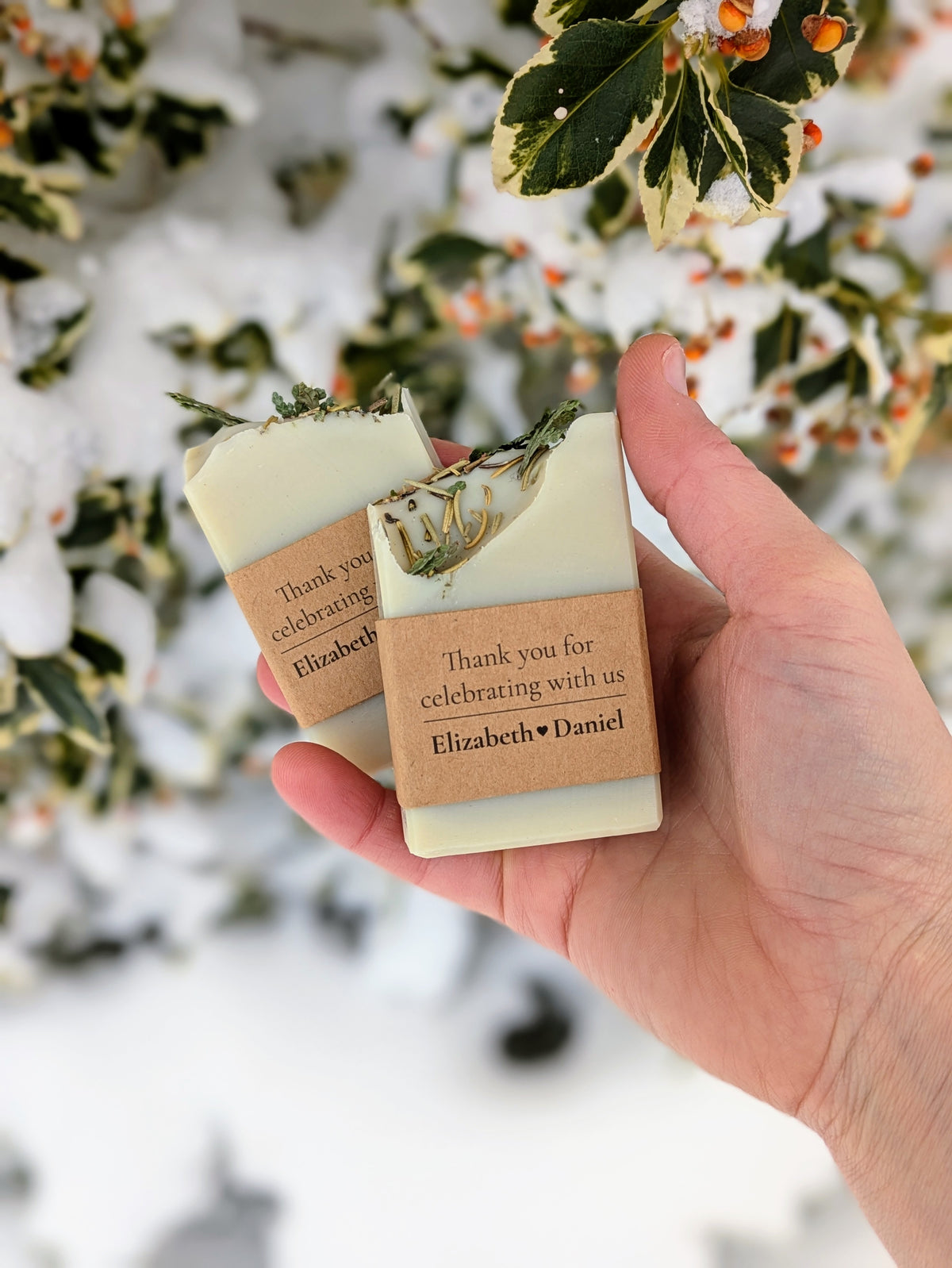 Hand holding two personalized soap bars with a snowy background