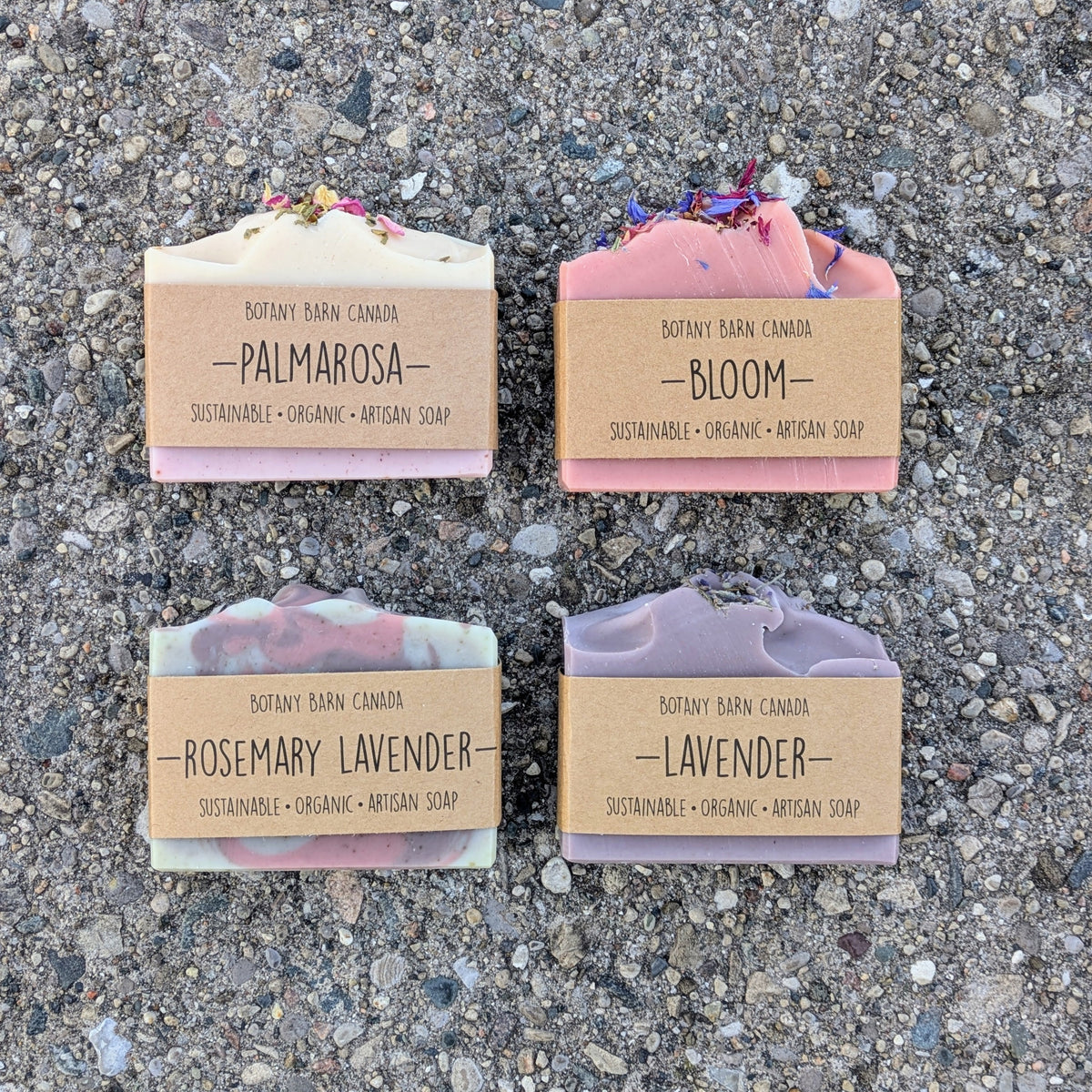 Four bars of soap with labels on a textured surface