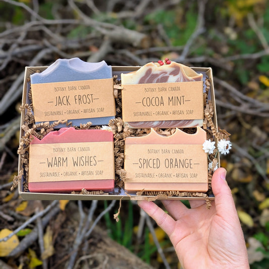 Hand holding a box of soap bars with branded Botany Barn  labels in front of a natural background