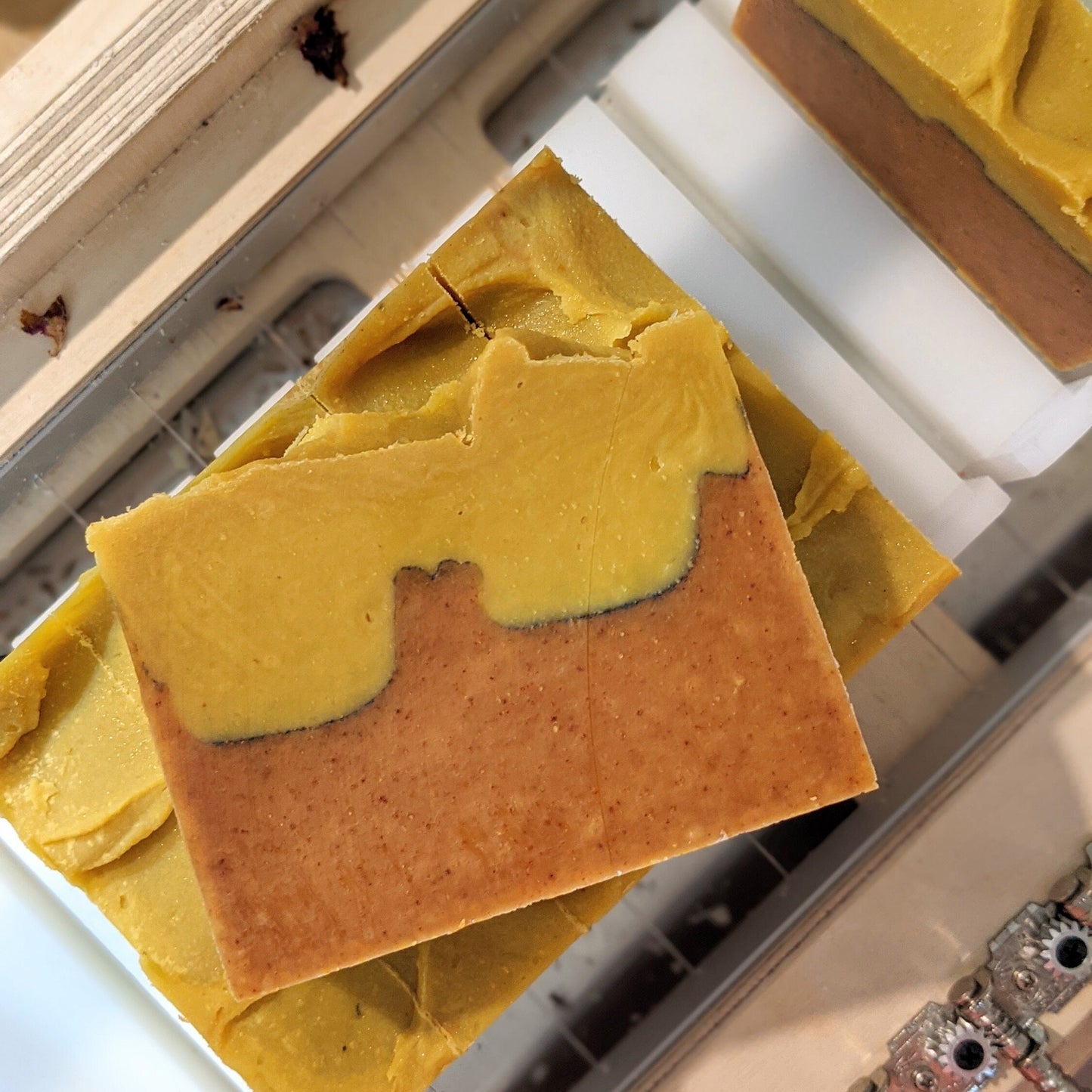 Bar of soap with a gradient from yellow to orange on a soap cutter