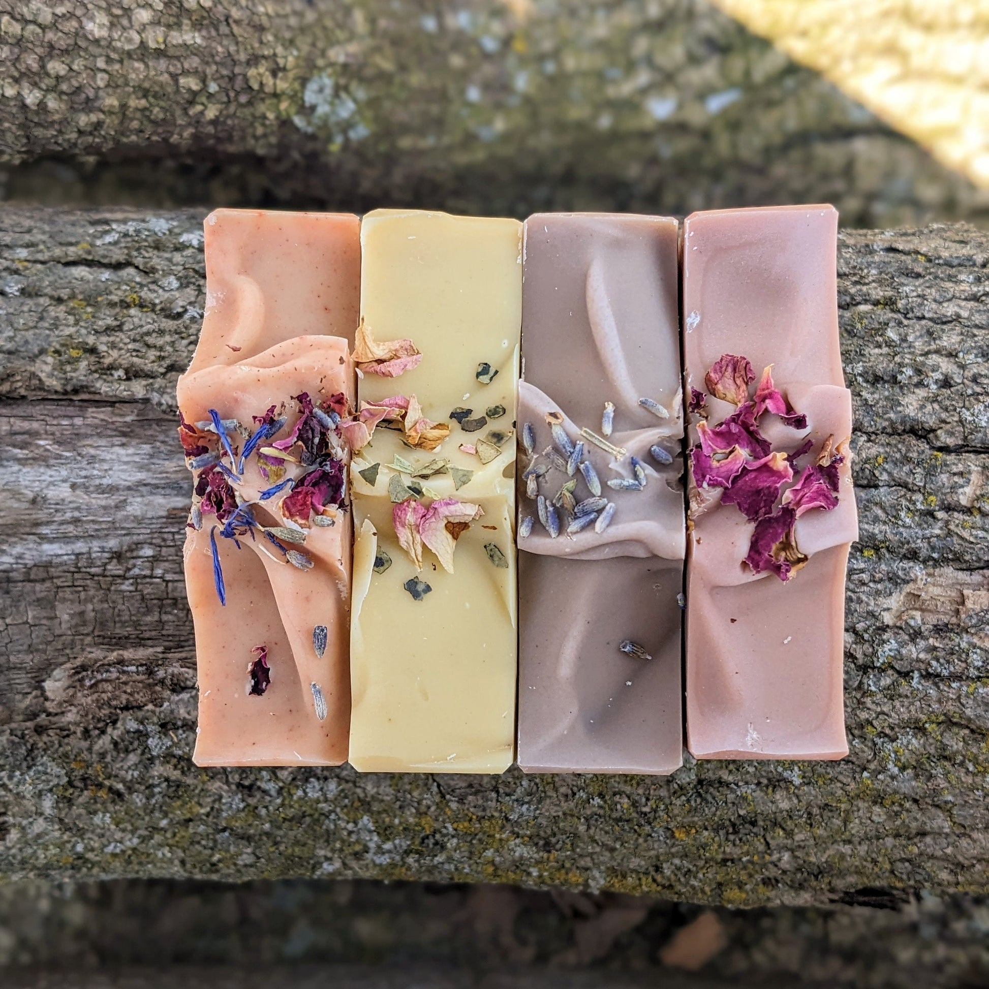 Four bars of soap with natural ingredients on a wooden surface