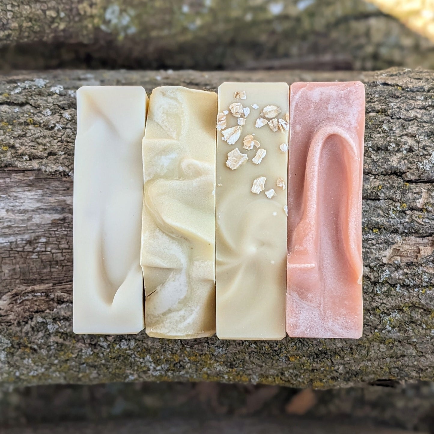 Four different bars of soap on a wooden surface
