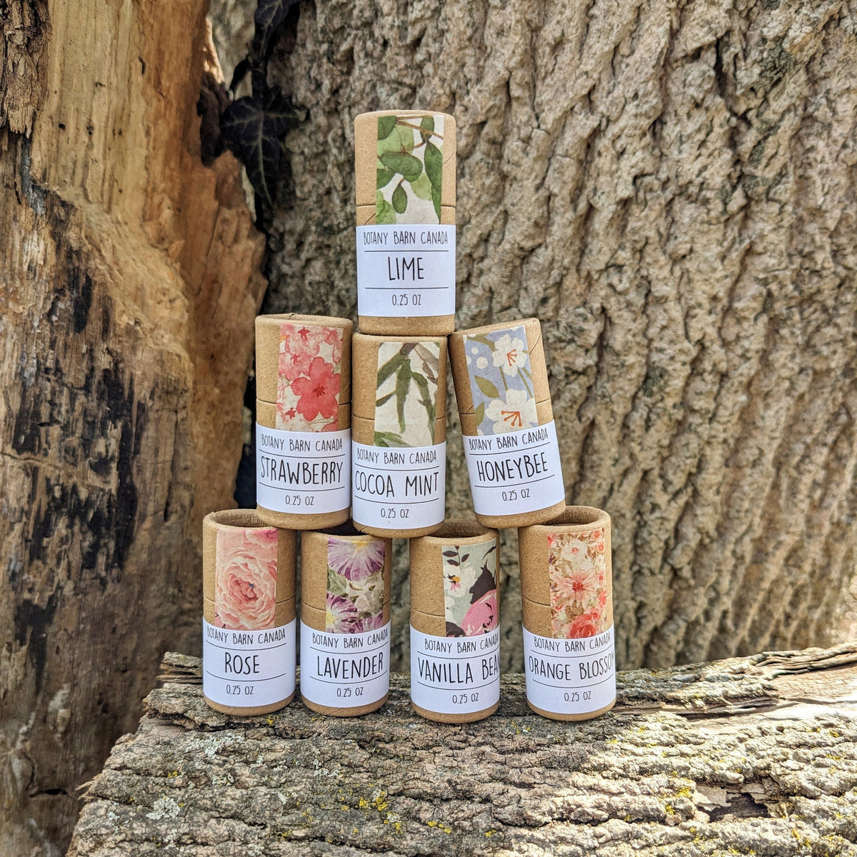 Eight eco-friendly lip balms with colourful labels stacked on a log