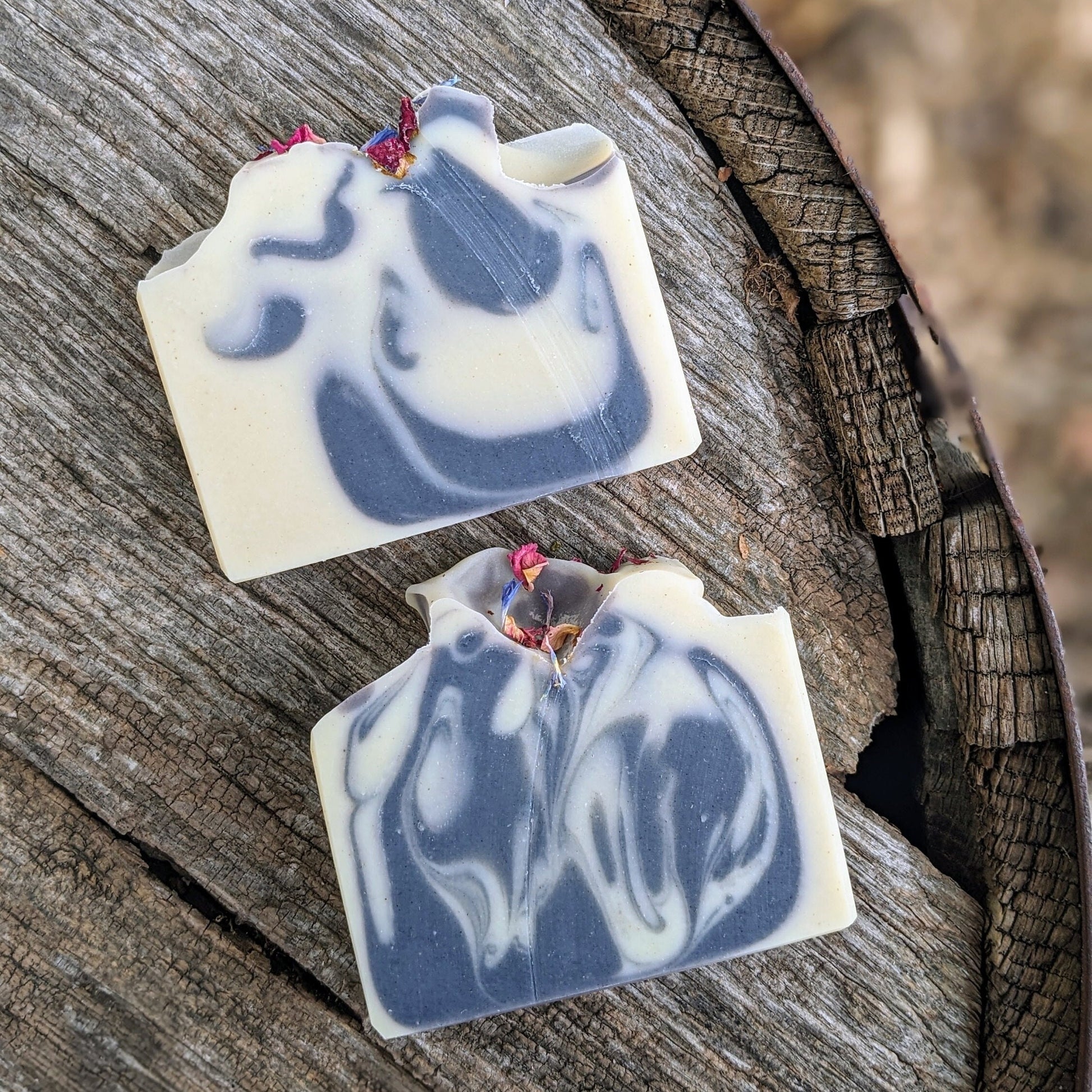 Two blue and white swirled soap bars on a wooden surface