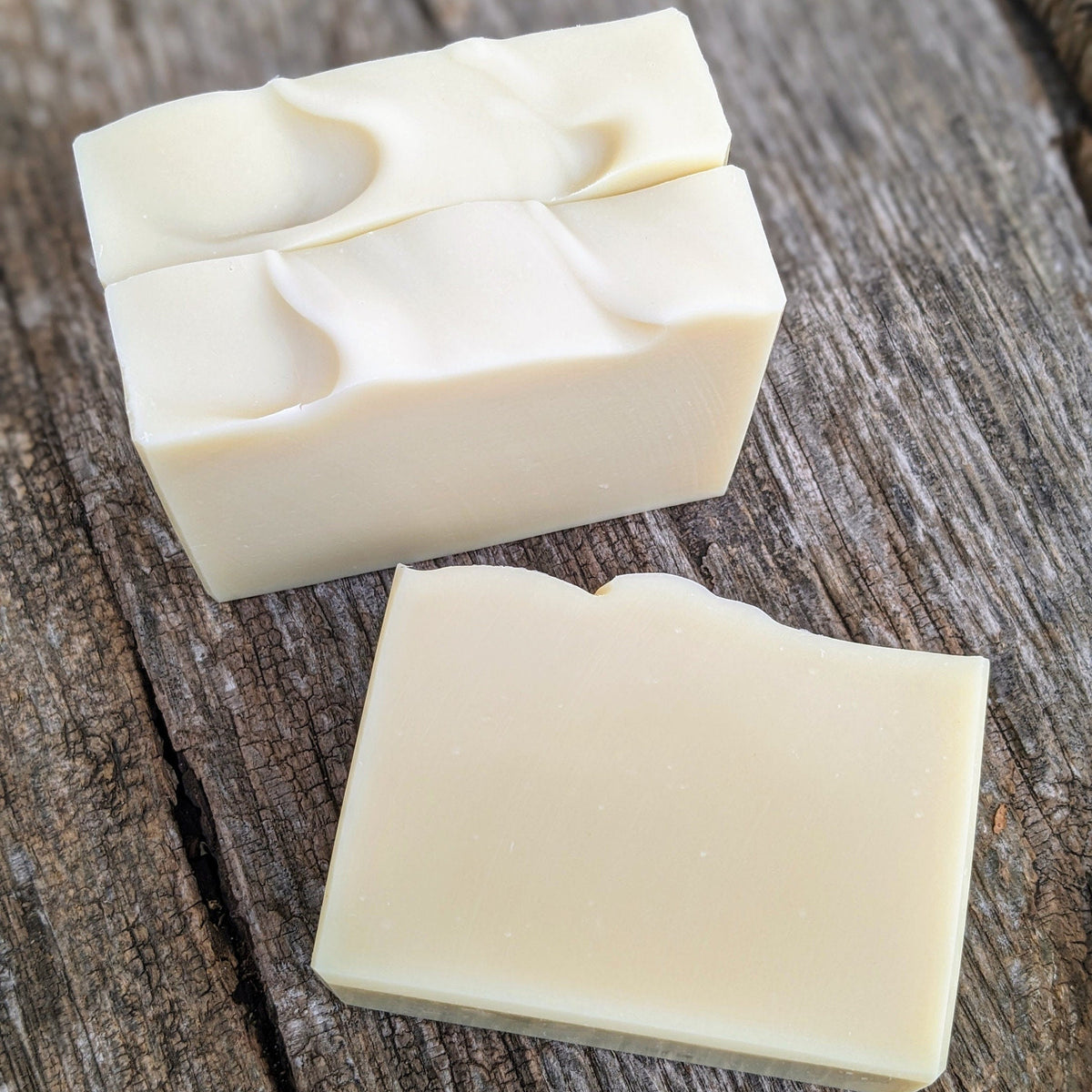 Two bars of white soap on a wooden surface