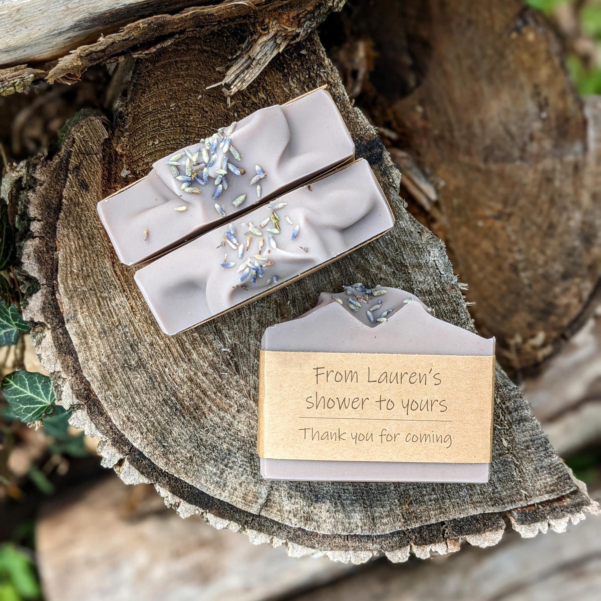 Handmade soap bars with floral decorations on top, wrapped in brown kraft paper with text 'From Lauren's shower to yours'.