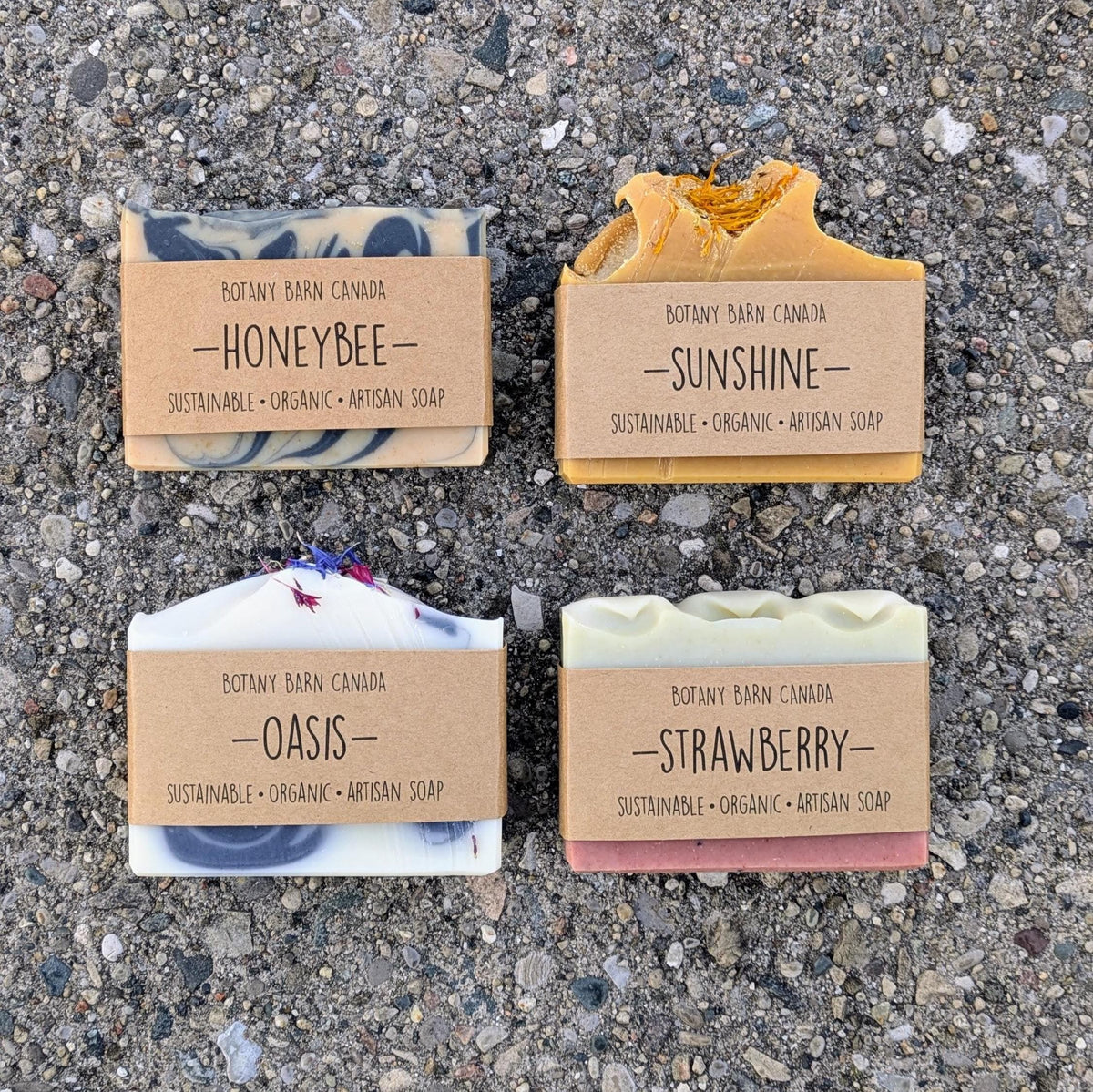 Four bars of soap with labels on a textured surface