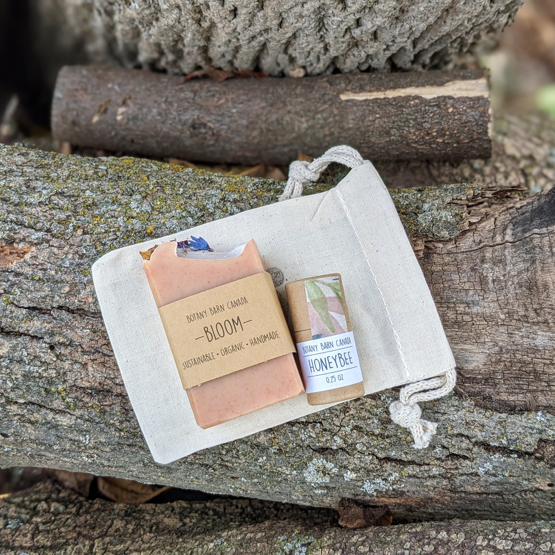 A mini soap bar and a tube of lip balm placed inside a beige muslin bag, set against a rustic wooden background.