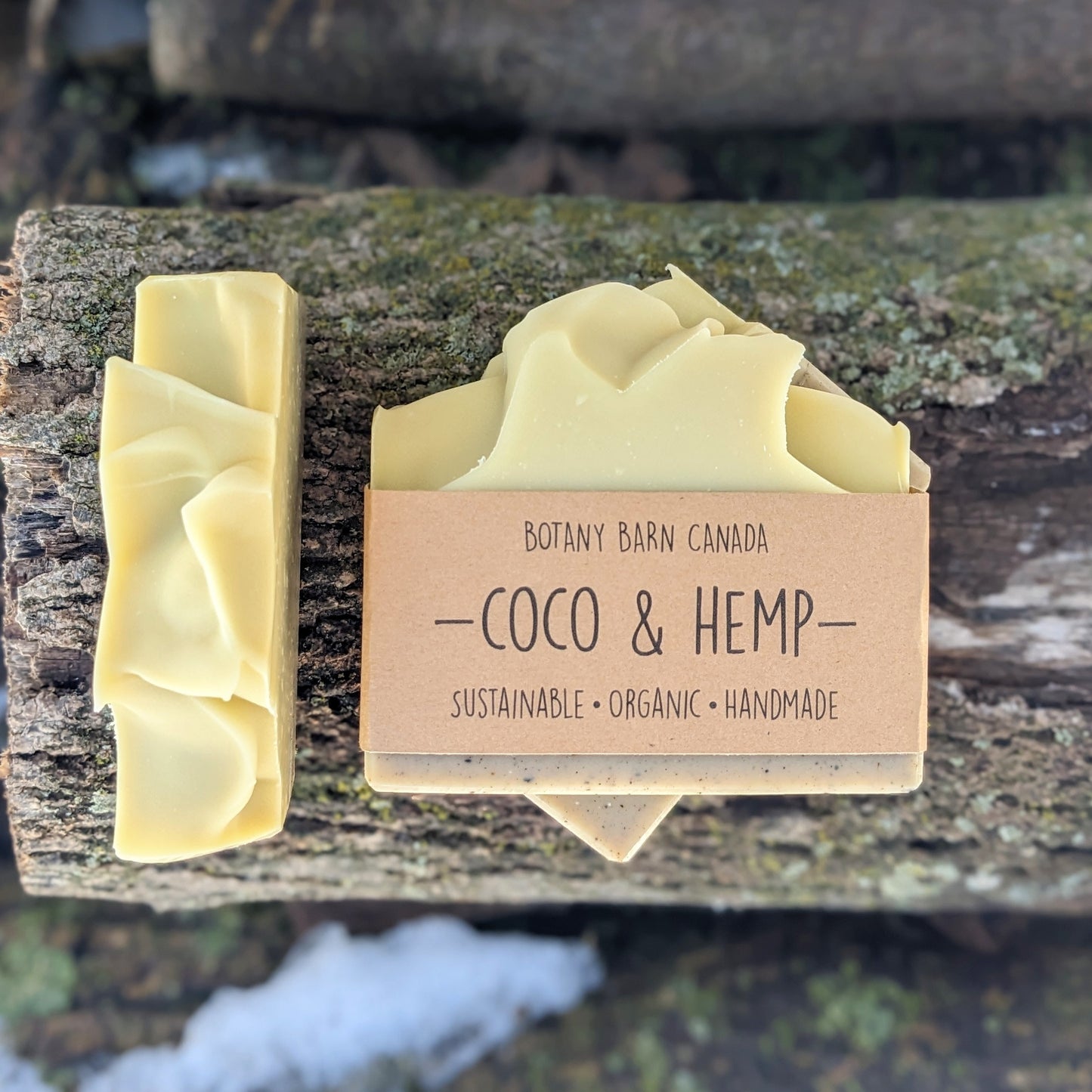 Bars of handmade artisan soap, top and front view. The soap is creamy yellow & beige in colour. A brown label reads the name of the company, Botany Barn Canada and the name of the soap, Coco & Hemp.