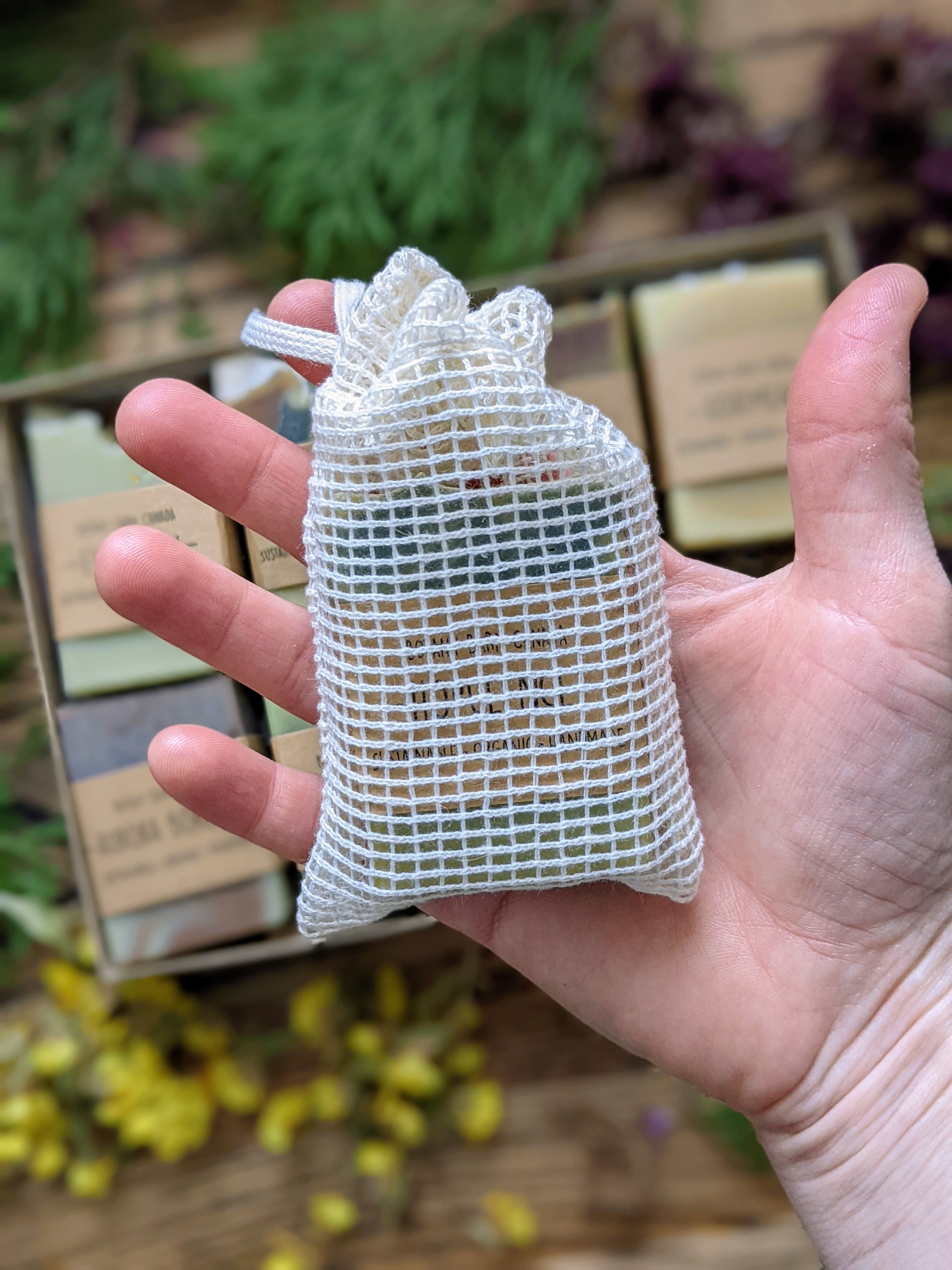 Hand holding a small mesh bag with a blurred natural background