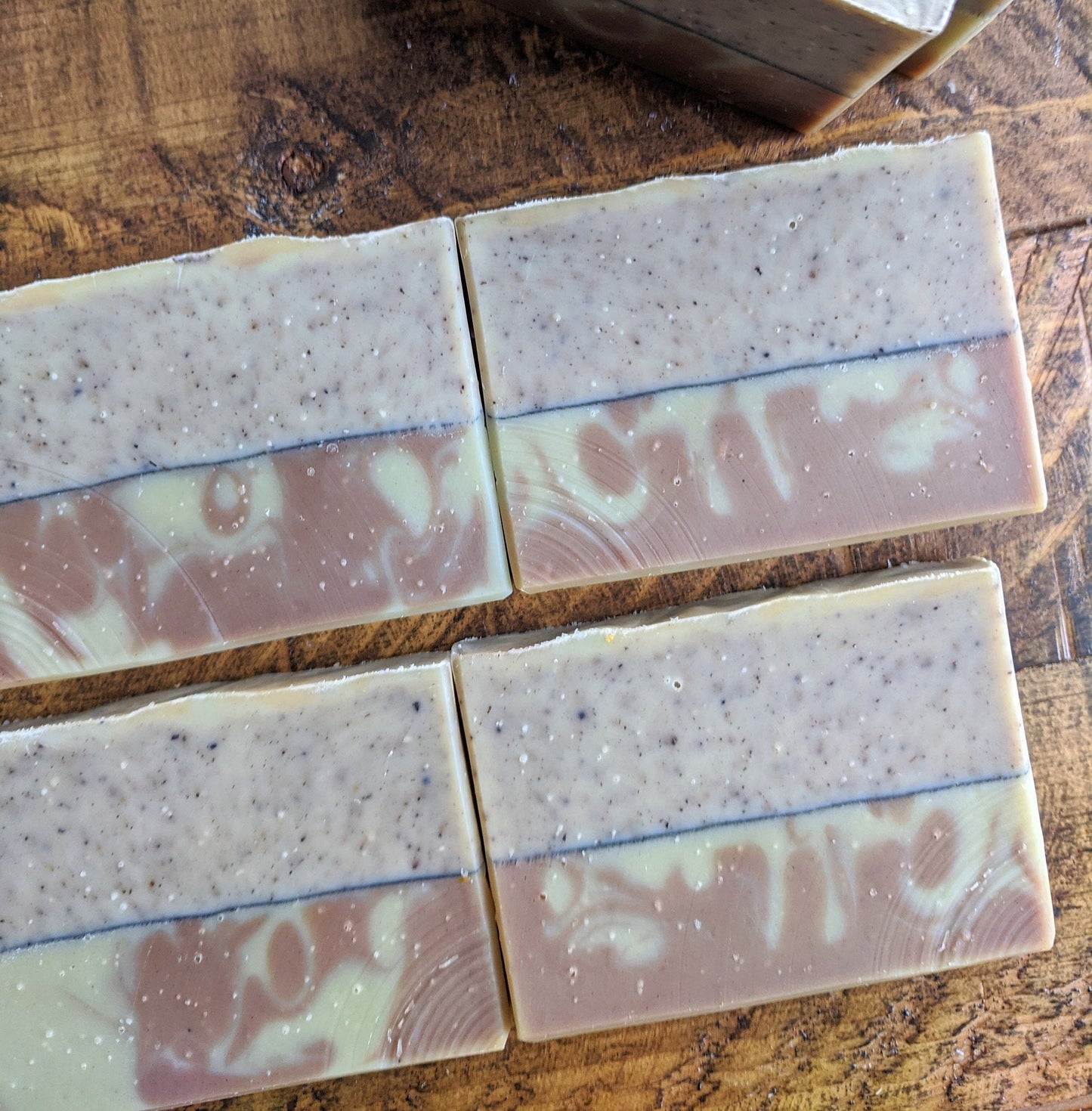 Four bars of layered soap on a wooden surface
