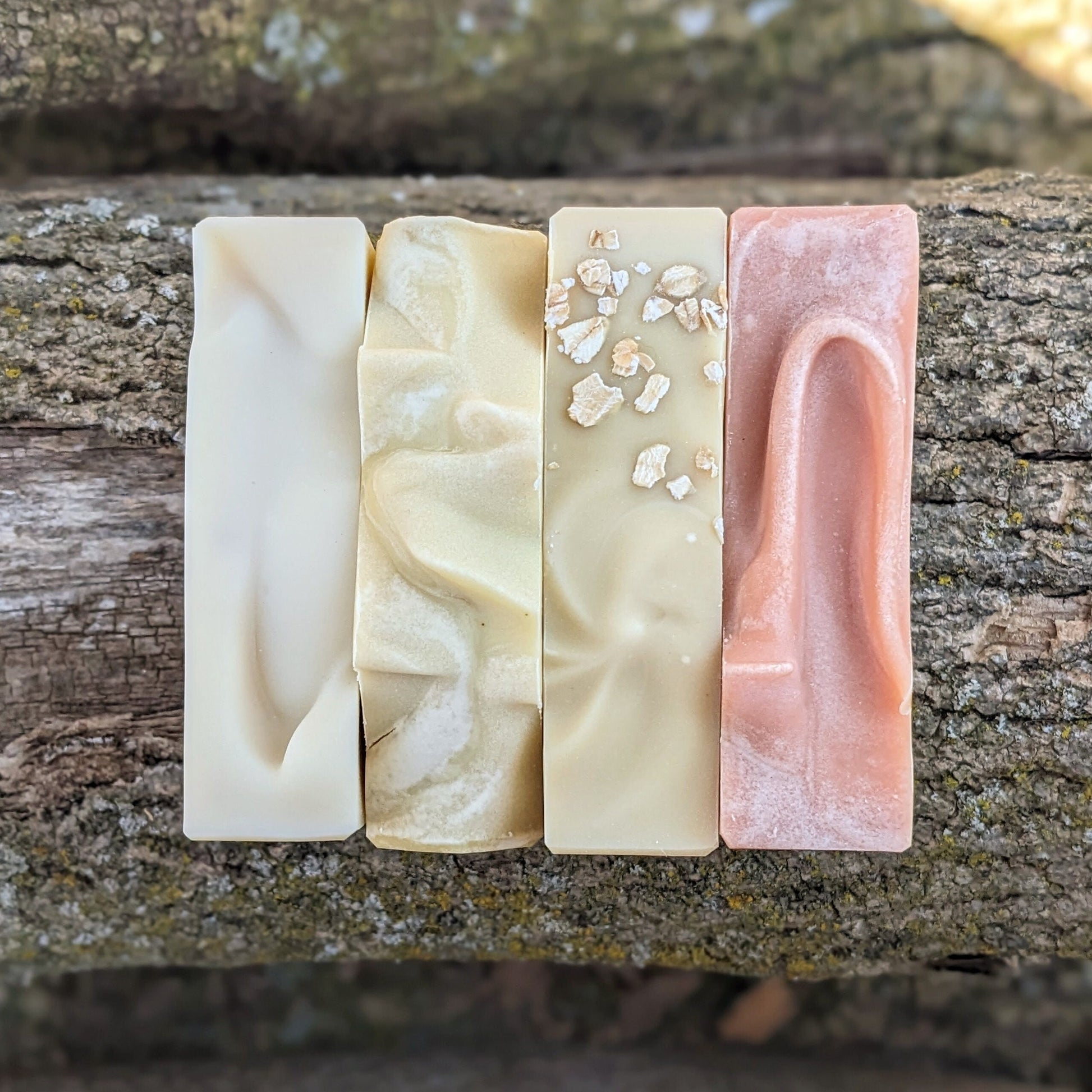 Four different bars of soap on a wooden surface