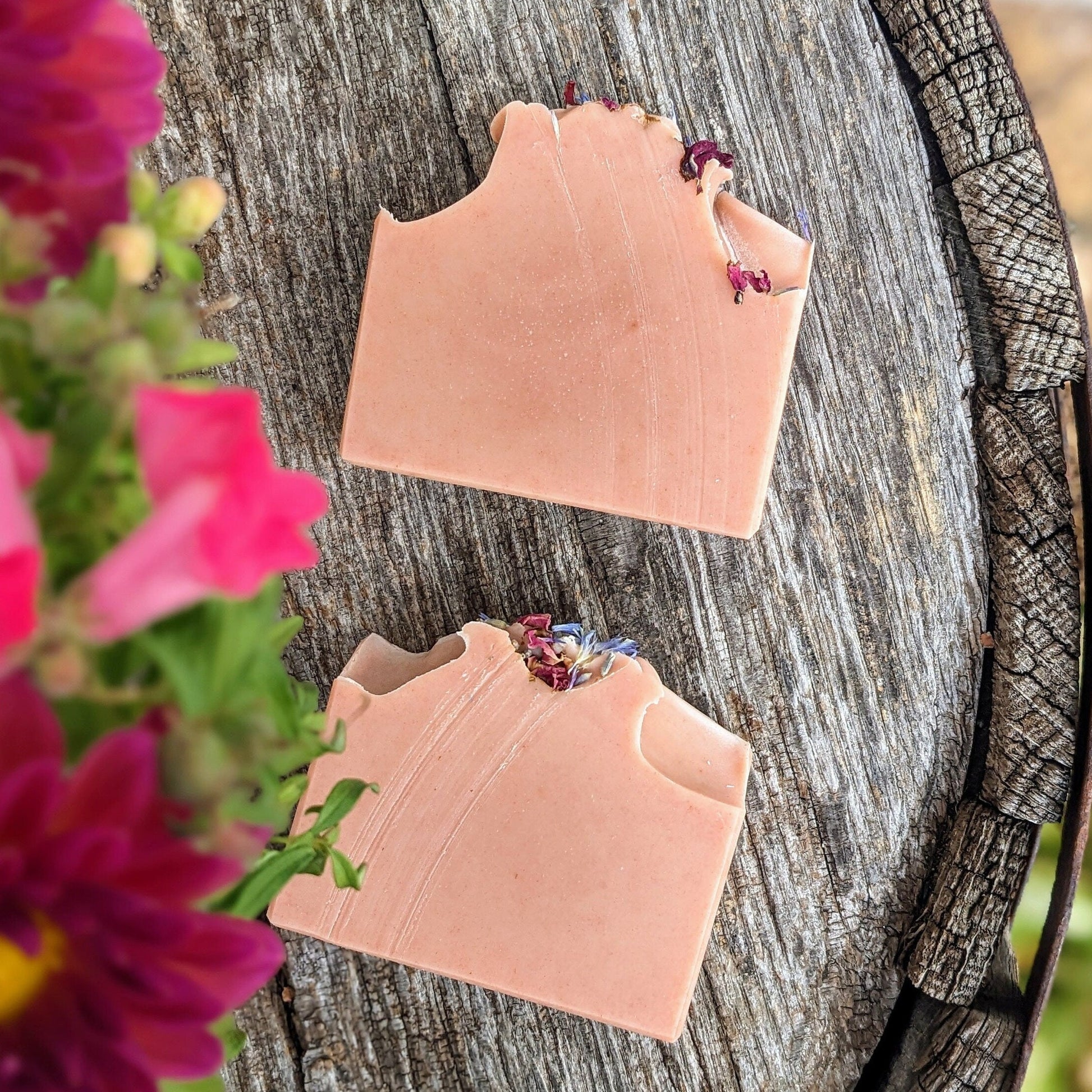 Two bars of pink soap displayed on a wooden surface