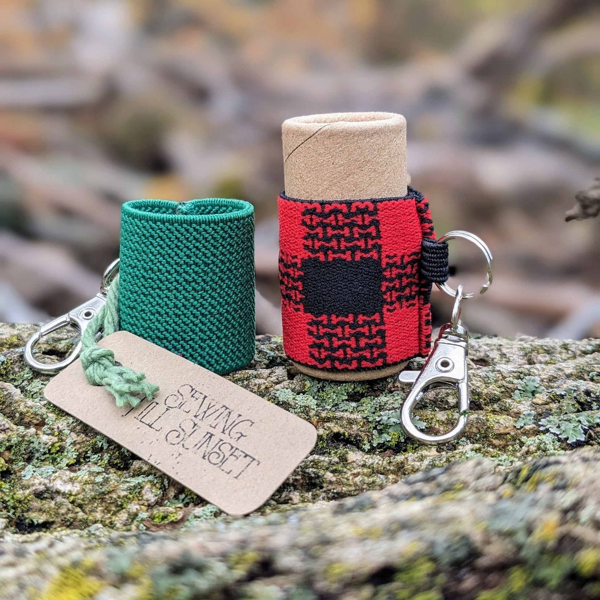 Two elastic lip balm holders with keychains, one green and one red and black. On display on a wooden surface.