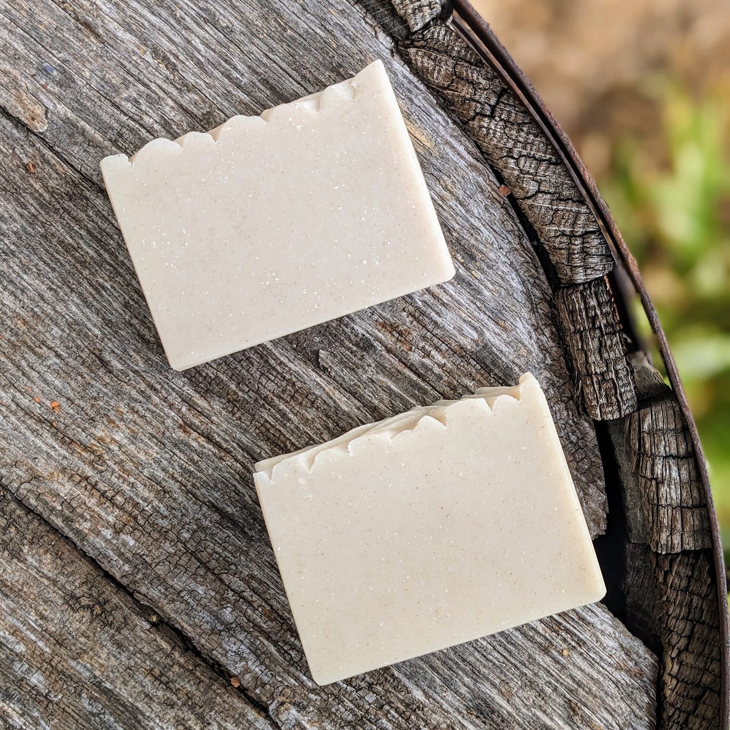 Two bars of soap on a wooden surface with a natural background