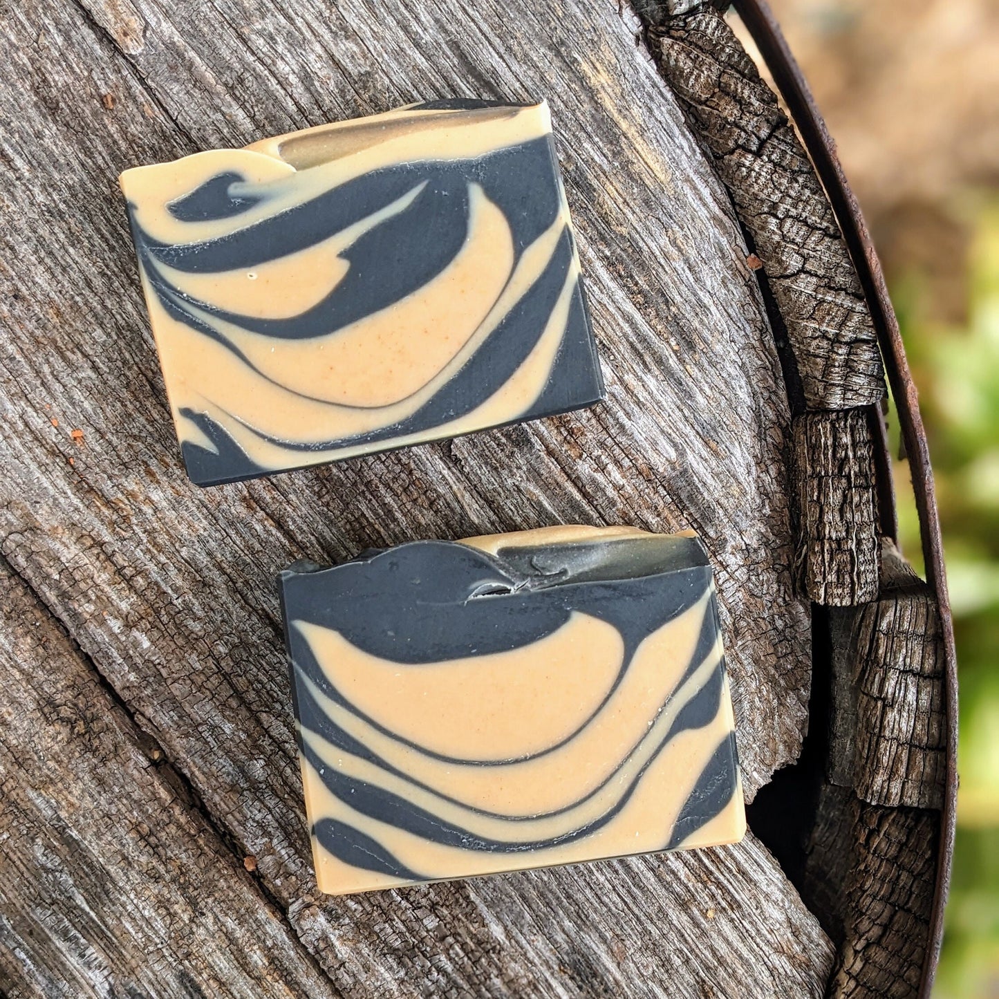 Two swirled soap bars on a wooden surface