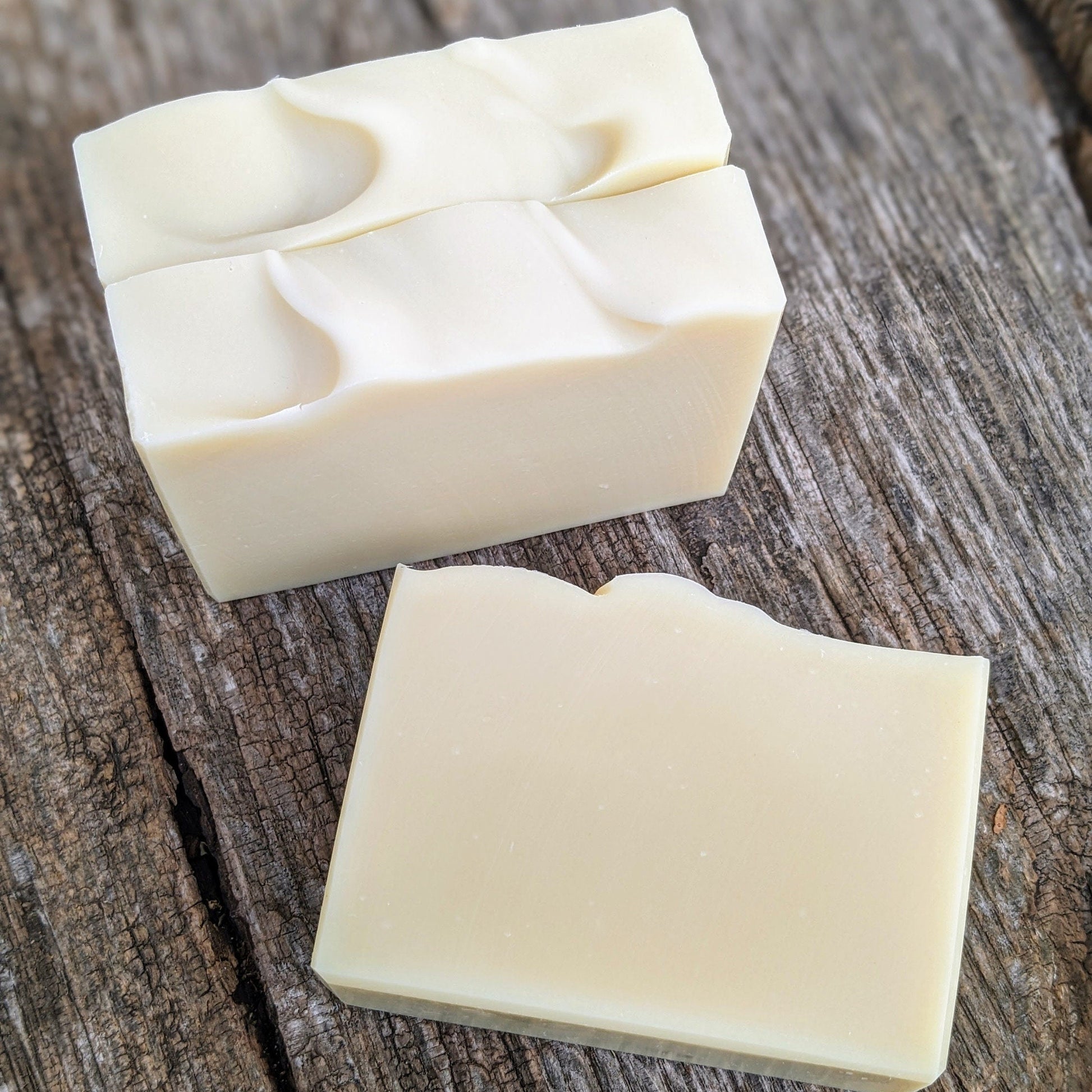 Two bars of white soap on a wooden surface