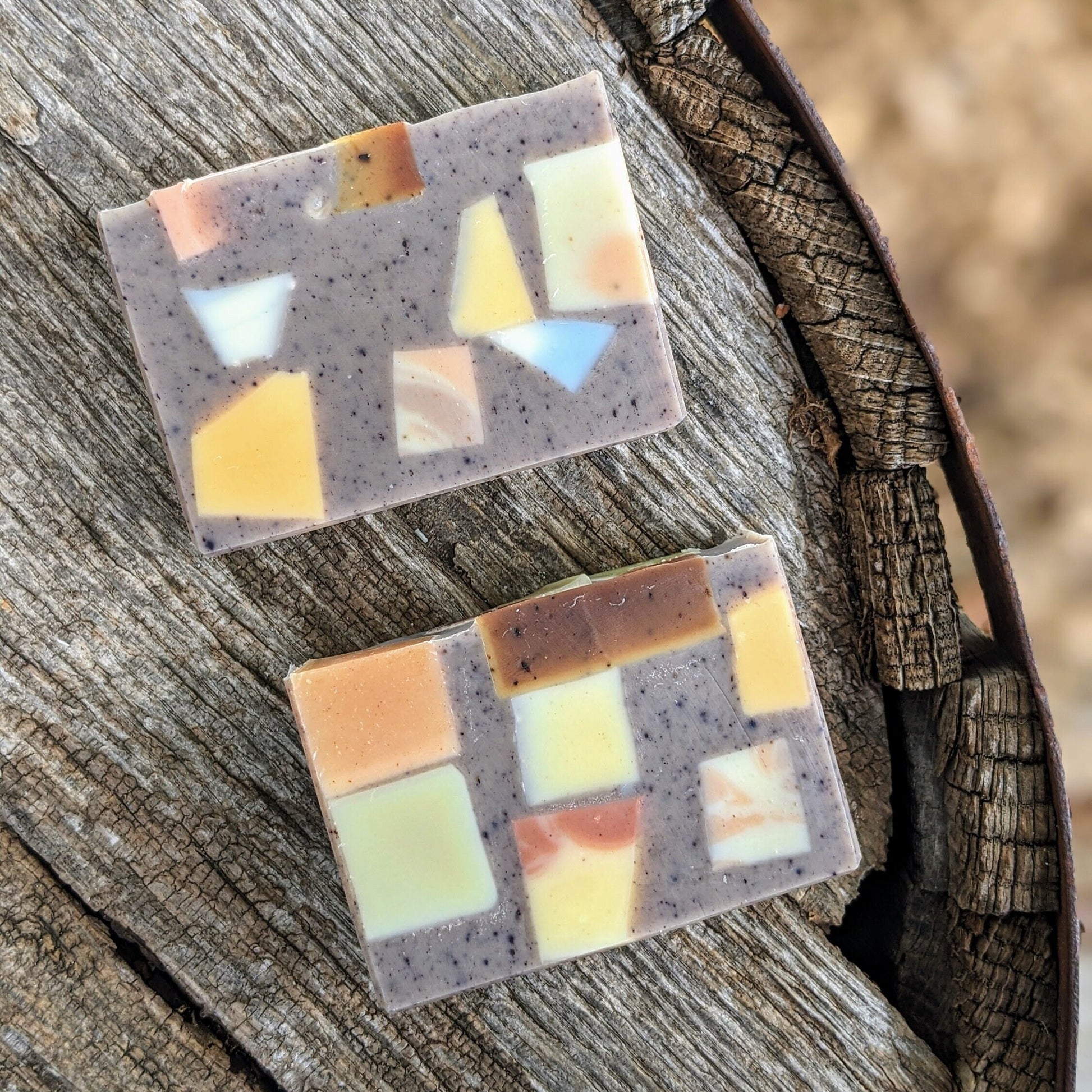 Two mosaic-patterned soap bars on a wooden surface